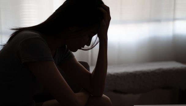 Depressed,Woman,Sitting,Alone,On,The,Bed,With,Hands,On