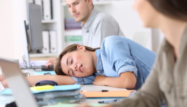 Fatigued,Employee,Sleeping,On,A,Desktop,At,Office,With,Her