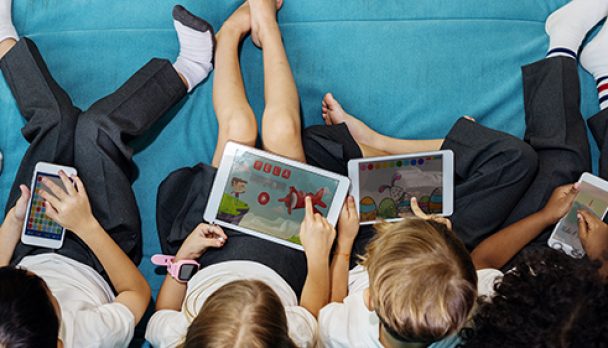 Group of diverse kindergarten students using digital devices aerial view flatlay